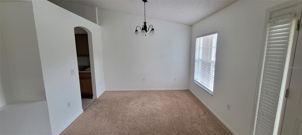 An empty dining area features beige carpet, white walls, a chandelier, and a window — 226 AGUA VISTA STREET, DEBARY, FL