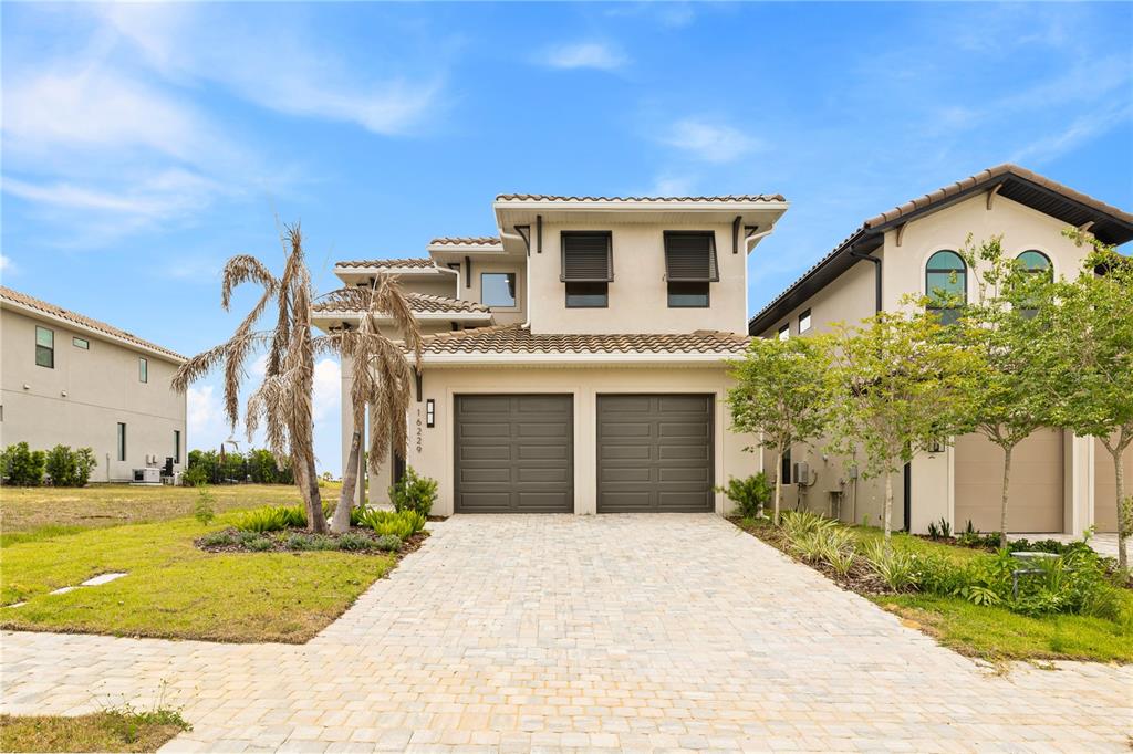 A two-story house with a two-car garage and a paved driveway under a blue sky — 16229 RAVENNA COURT, BELLA COLLINA, FL