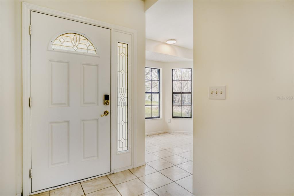 An entryway features a white front door with a glass sidelight and tiled flooring — 2627 TALON COURT, ORLANDO, FL