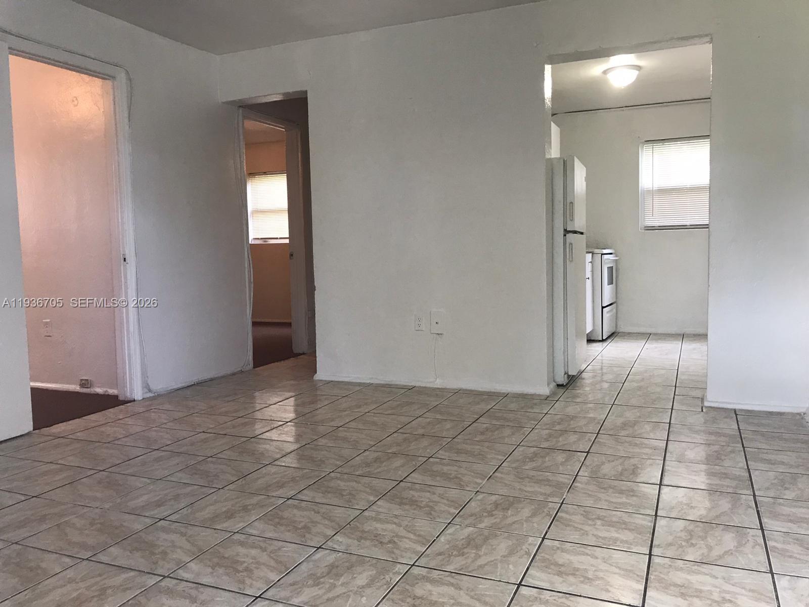 A room with light-colored tile flooring leads to a kitchen and a separate doorway — 1948 NW 2nd Ct # 5, Miami FL 33136, MIAMI, FL