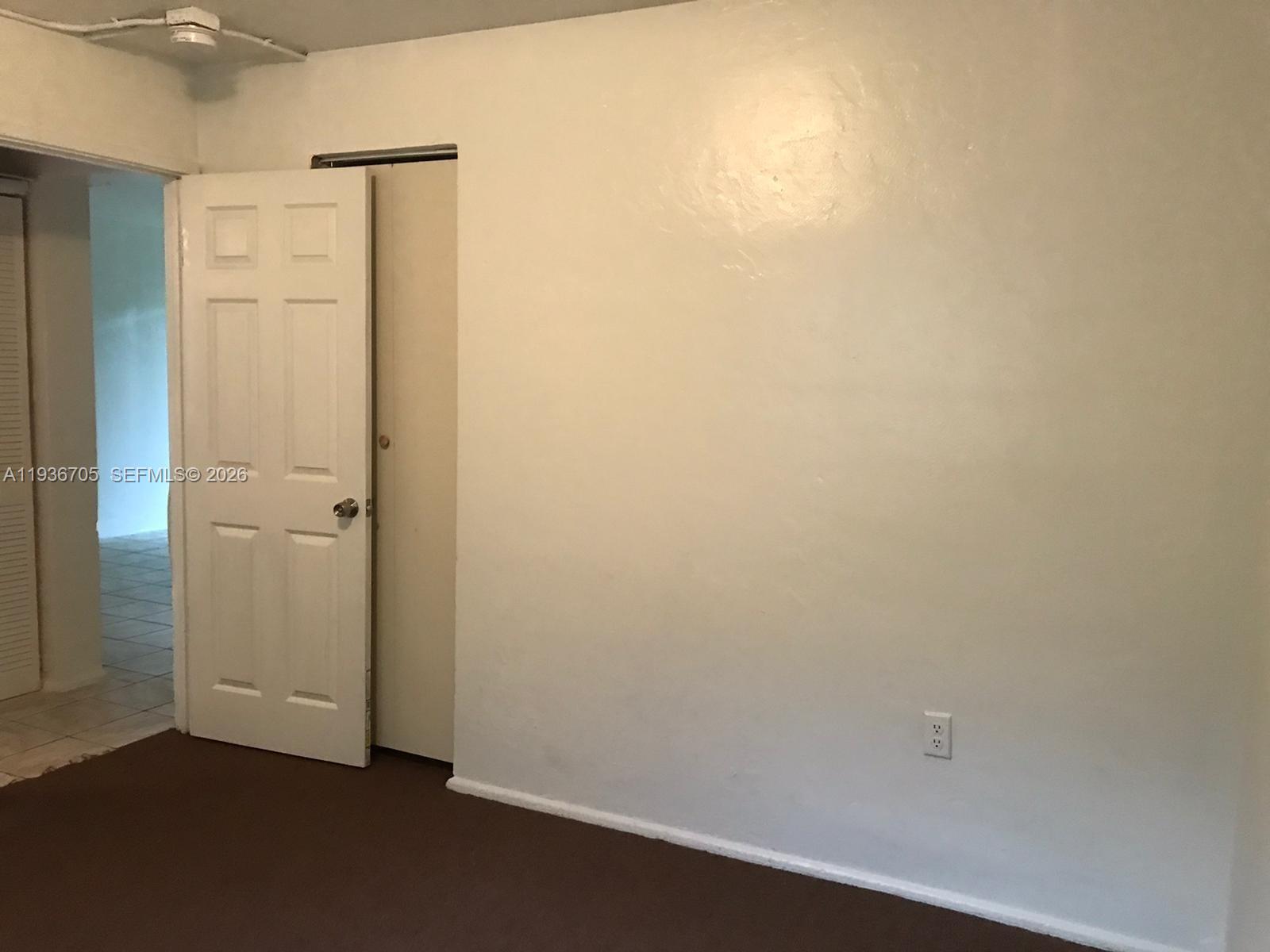 A room with brown carpet, white walls, a white door, and a wall outlet — 1948 NW 2nd Ct # 5, Miami FL 33136, MIAMI, FL