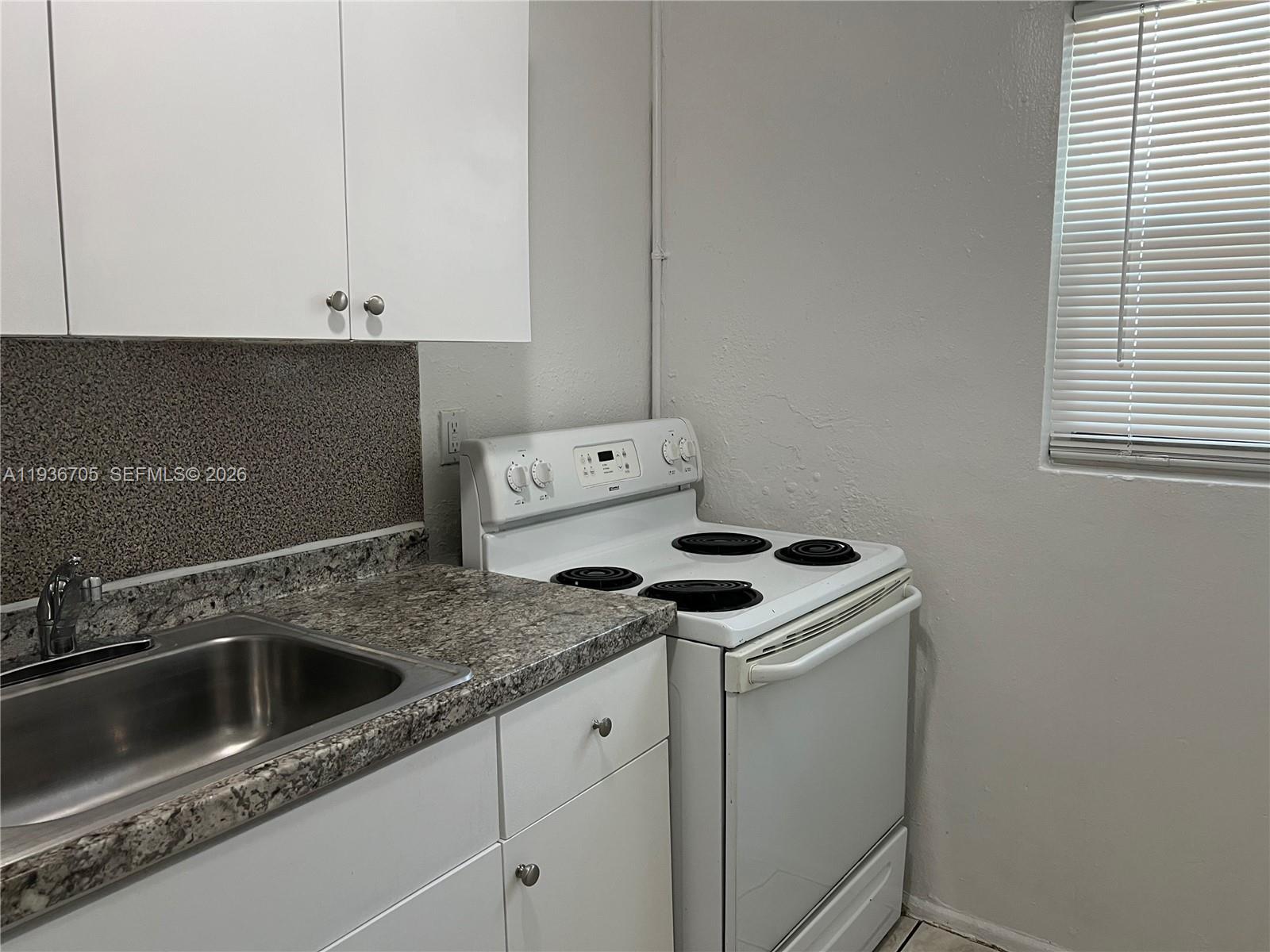 A kitchen features white cabinets, a granite countertop, a stainless steel sink, and a stove — 1948 NW 2nd Ct # 5, Miami FL 33136, MIAMI, FL