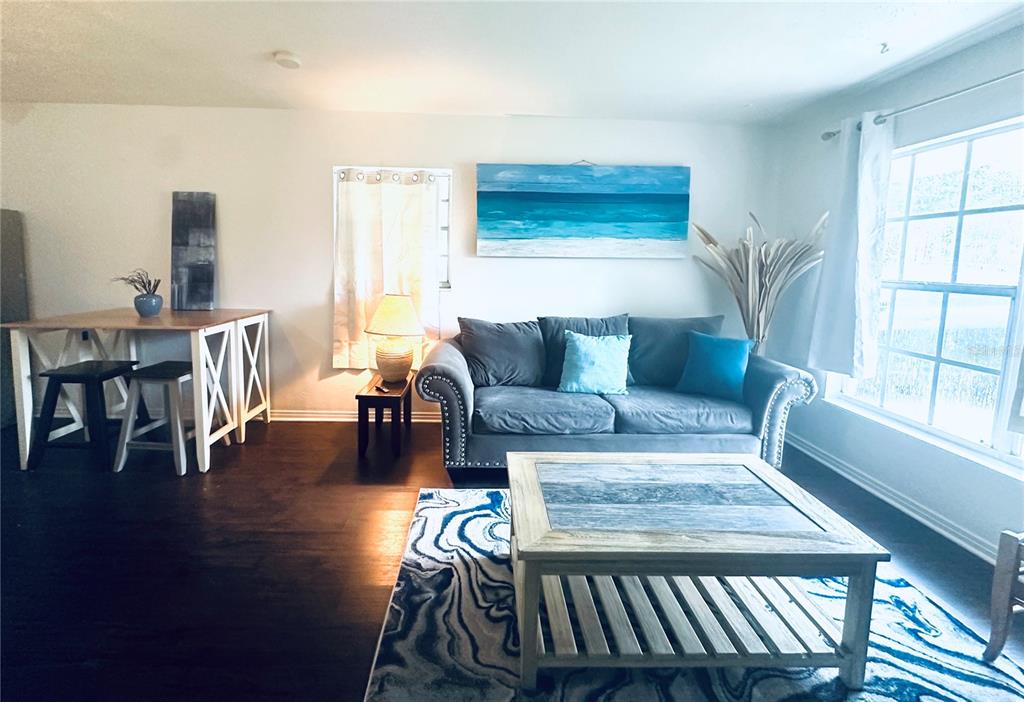 A living room features a grey sofa, a wooden coffee table, and a dining area — 4716 W WISCONSIN AVENUE, TAMPA, FL