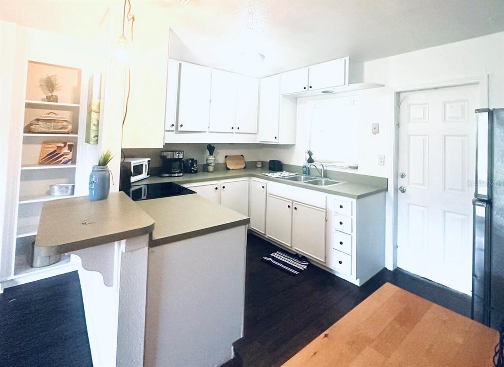 A kitchen with white cabinets, green countertops, dark wood floors, and an open shelving unit — 4716 W WISCONSIN AVENUE, TAMPA, FL