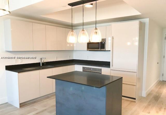 A modern kitchen features white cabinetry, a dark island, black countertops, and three pendant lights — 1010 Brickell Ave # 4609, Miami FL 33131, MIAMI, FL