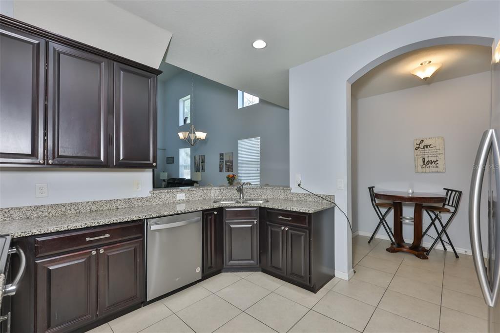 A kitchen with dark wood cabinets, granite countertops, and a breakfast nook with a table — 3019 OLD FULTON PLACE, BRANDON, FL