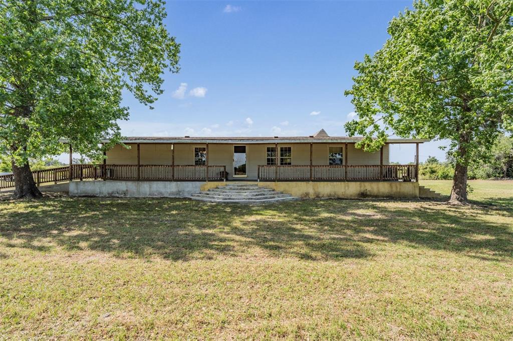 A single-story house with a wide front porch and wooden railing sits on a lawn — 6606 GATOR RANCH STREET, PLANT CITY, FL