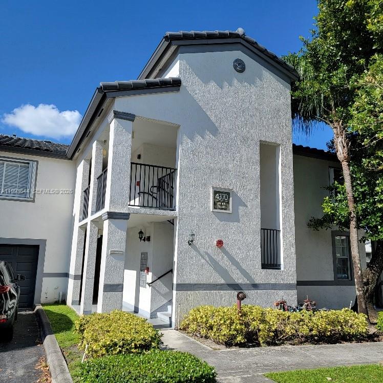 A two-story stucco building with a balcony, dark trim, and a small front garden — 4370 NW 107th Ave # 107, Doral FL 33178, DORAL, FL