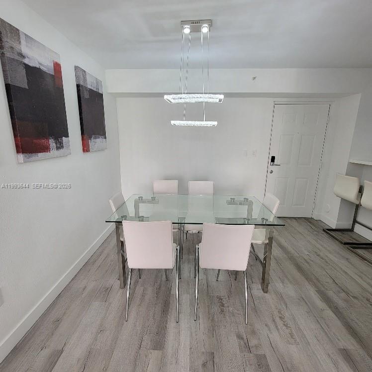 A dining room features a glass-top table, six chairs, and a modern rectangular pendant light — 4370 NW 107th Ave # 107, Doral FL 33178, DORAL, FL