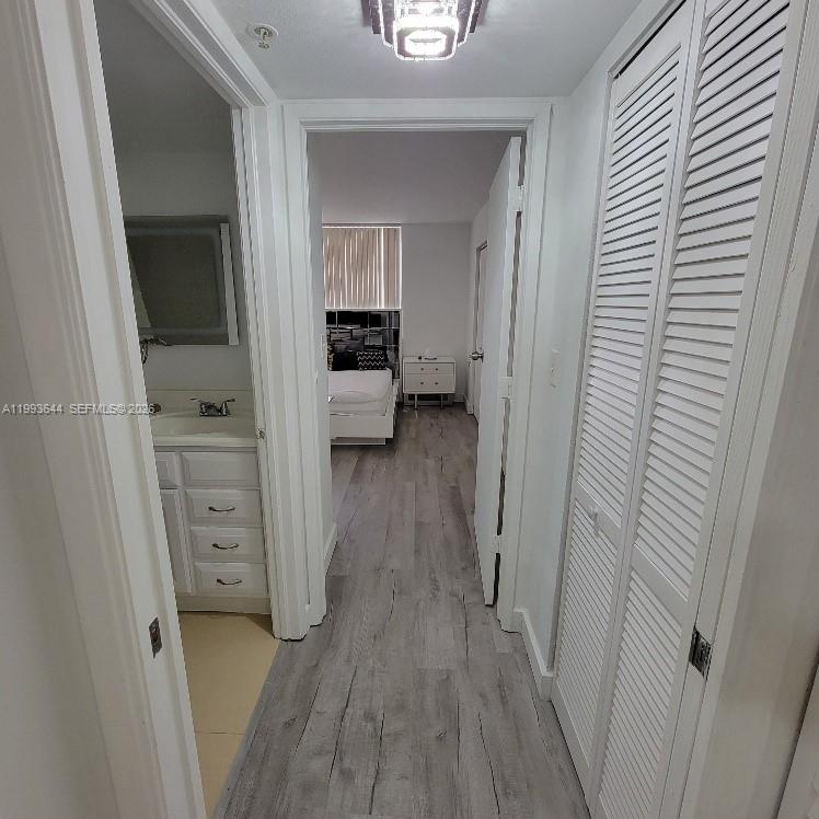 A hallway leads to a bedroom, featuring a bathroom vanity on the left and closet doors — 4370 NW 107th Ave # 107, Doral FL 33178, DORAL, FL