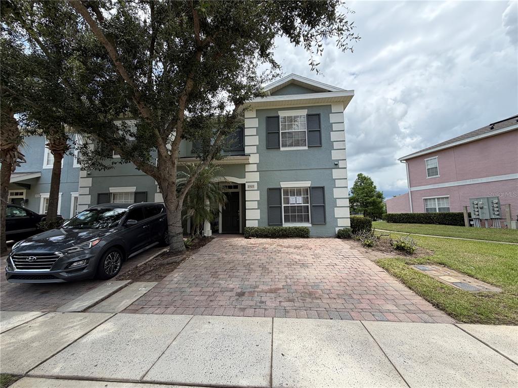A two-story house with a brick paver driveway and a dark gray car parked outside — 2425 CARAVELLE CIRCLE, KISSIMMEE, FL