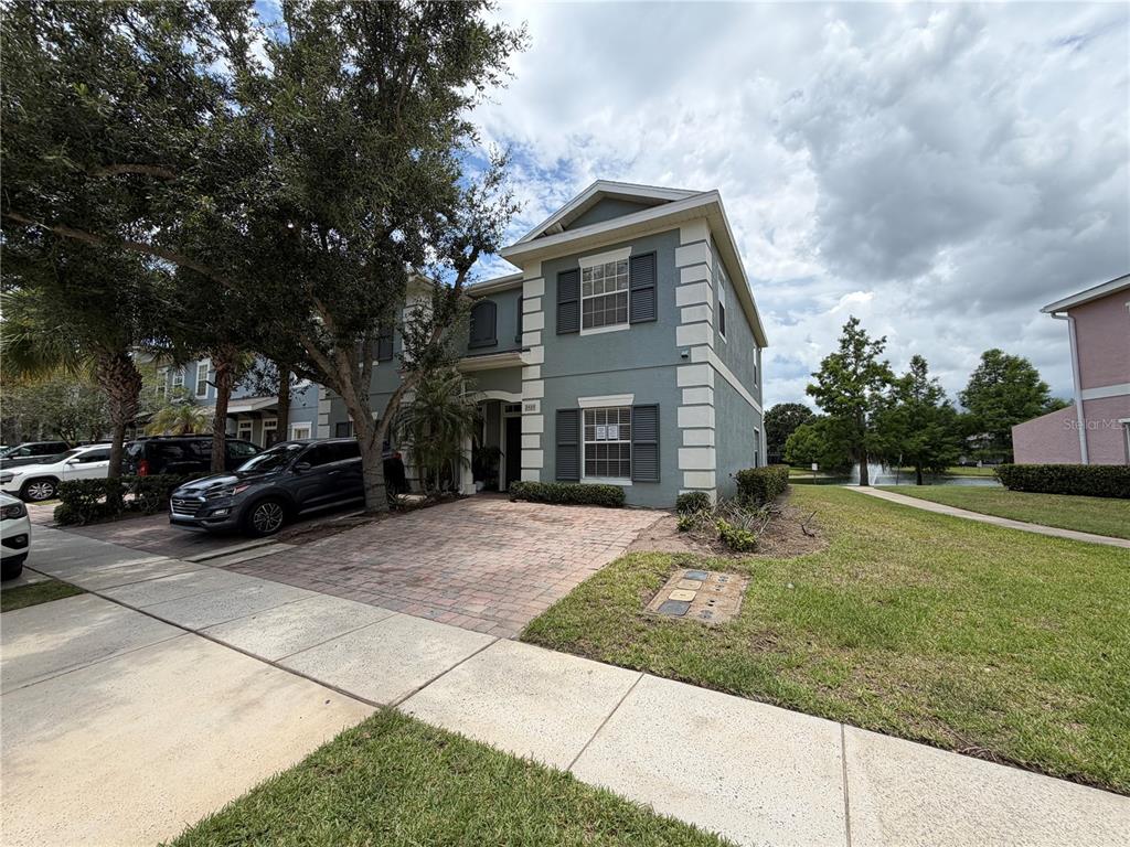 A two-story house with a paved driveway, gray stucco exterior, and a side lawn — 2425 CARAVELLE CIRCLE, KISSIMMEE, FL