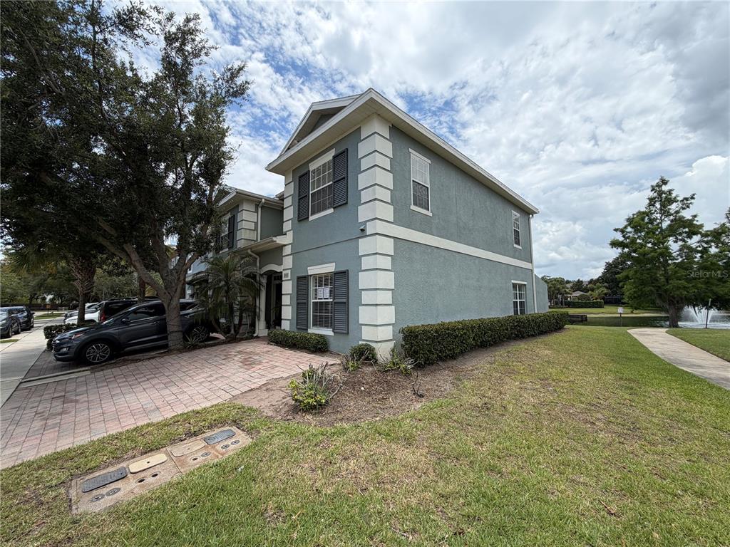 A two-story house with blue stucco siding and white corner quoins sits near a pond — 2425 CARAVELLE CIRCLE, KISSIMMEE, FL