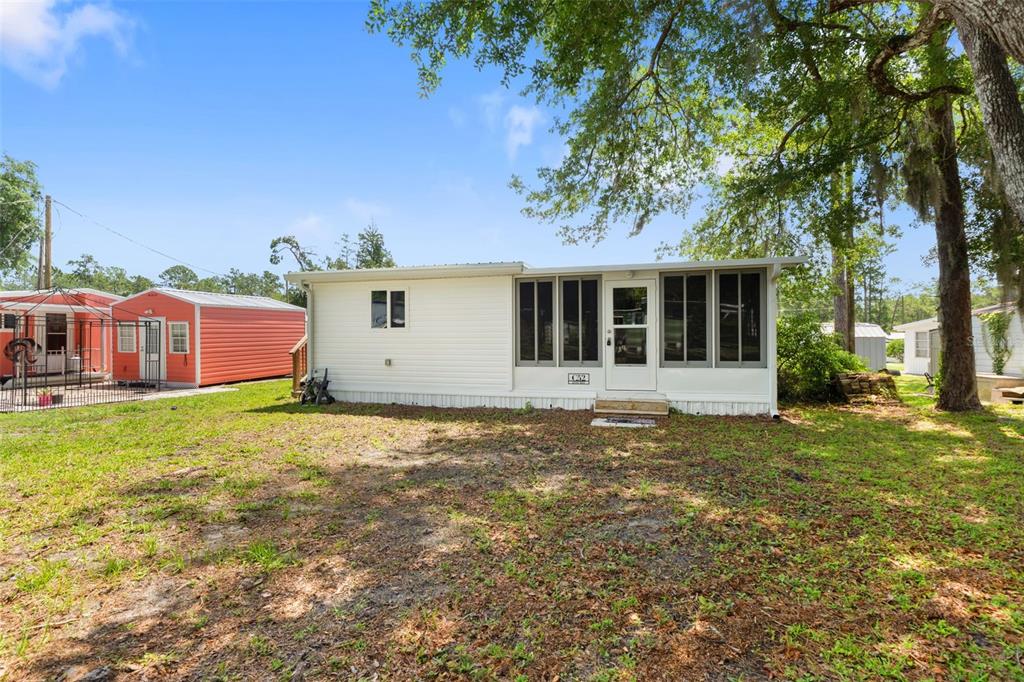 A white mobile home with a screened-in porch sits on a grassy lot with trees — 2092 CULBREATH ROAD UNIT C52, BROOKSVILLE, FL