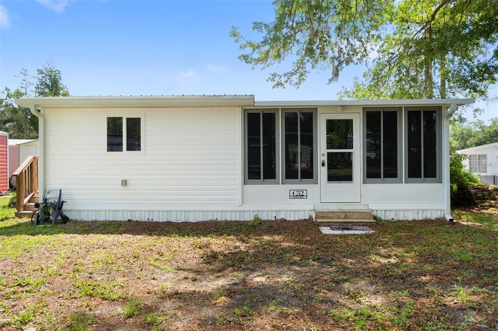 A white mobile home features a screened-in porch, a metal roof, and a wooden staircase — 2092 CULBREATH ROAD UNIT C52, BROOKSVILLE, FL