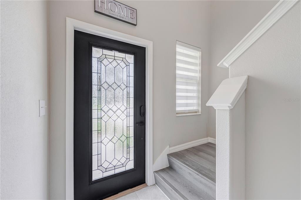 An entryway features a black front door with a glass insert and stairs with wood-look flooring — 5522 APPLETON SHORE DRIVE, APOLLO BEACH, FL