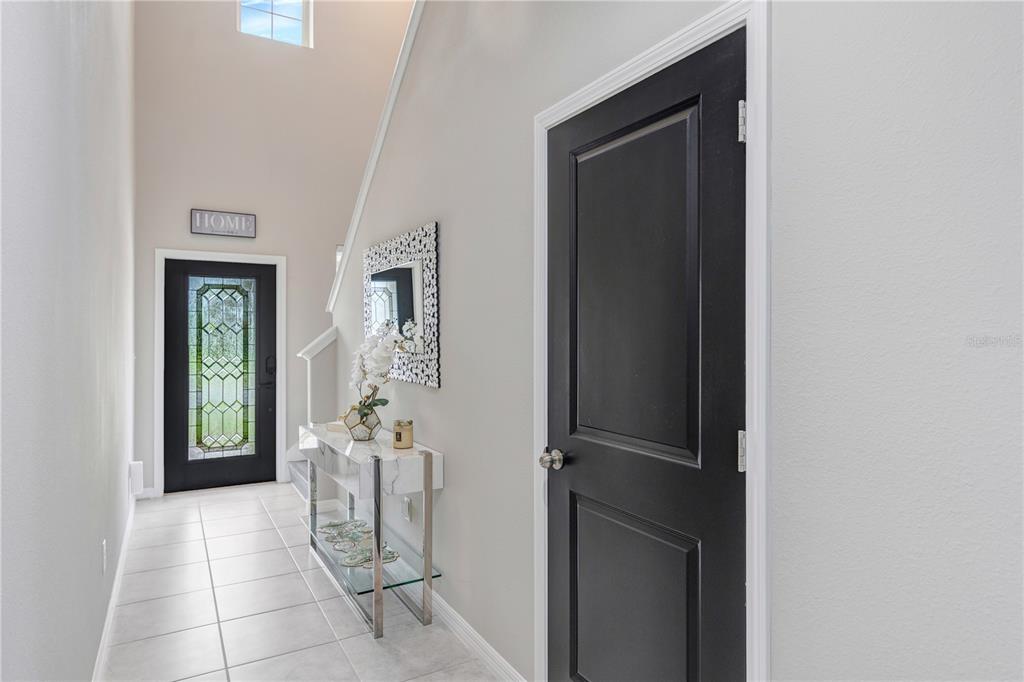 A bright entryway features a black front door, a marble console table, and a black door — 5522 APPLETON SHORE DRIVE, APOLLO BEACH, FL