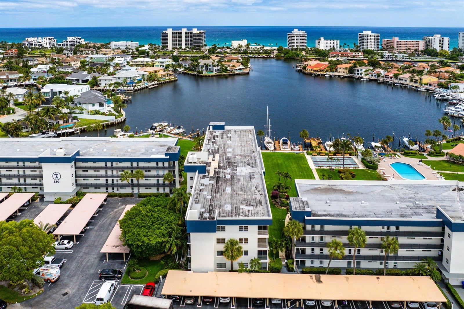 An aerial view shows apartment buildings with parking lots and a pool beside a canal — 3351 Spanish Trail # 212, Delray Beach FL 33483, DELRAY BEACH, FL