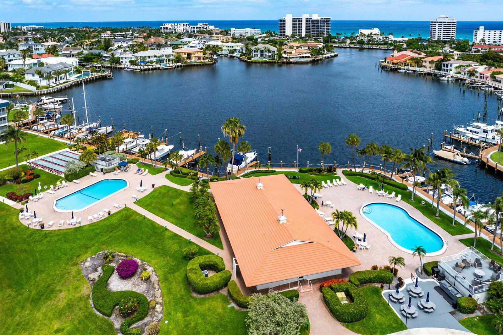 An aerial view shows a community clubhouse with two swimming pools, landscaping, and boat docks — 3351 Spanish Trail # 212, Delray Beach FL 33483, DELRAY BEACH, FL