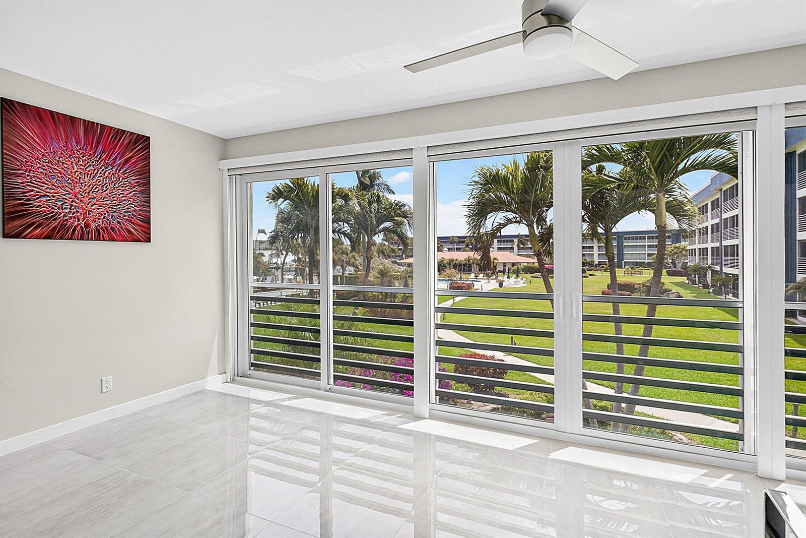 A bright room with white tile floors and large sliding glass doors overlooking a courtyard — 3351 Spanish Trail # 212, Delray Beach FL 33483, DELRAY BEACH, FL