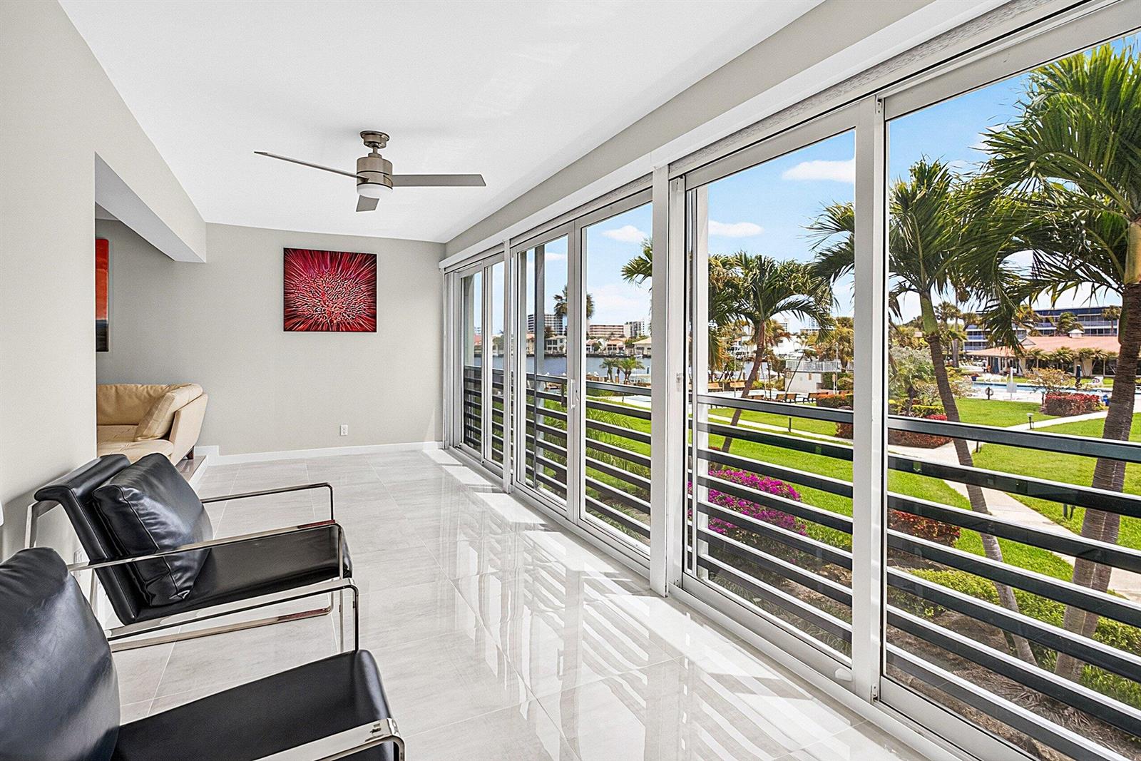 A sunroom with tile floors, black leather chairs, and sliding glass doors overlooking a lawn — 3351 Spanish Trail # 212, Delray Beach FL 33483, DELRAY BEACH, FL