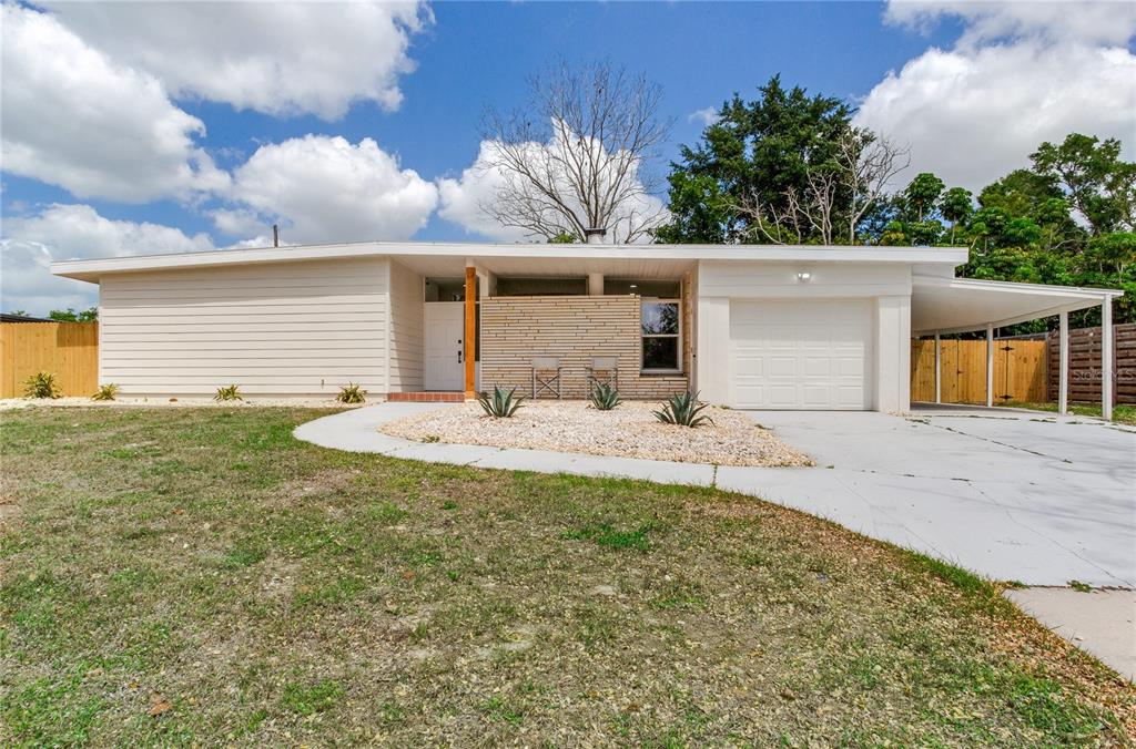 The exterior of a mid-century modern home features a brick patio, stone wall, and walkway — 2753 VALENCIA DRIVE, SARASOTA, FL