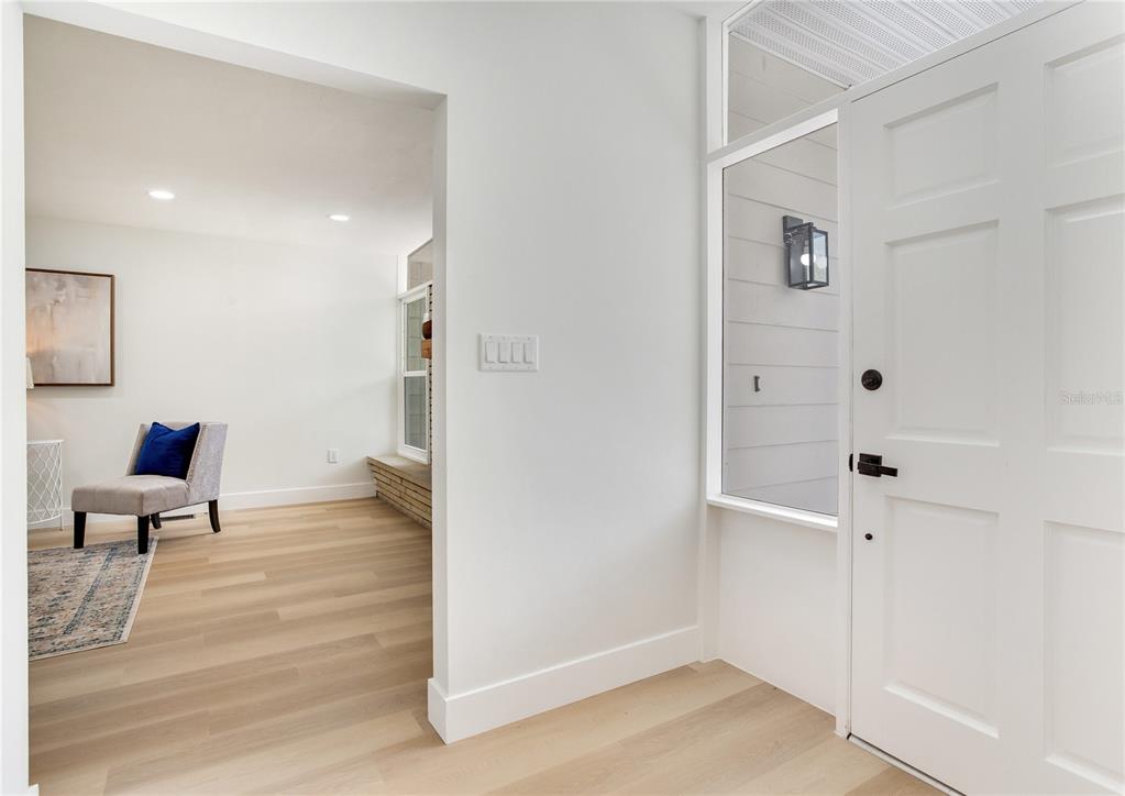 A bright, open-concept living area features light wood flooring, neutral walls, and a dining nook — 2753 VALENCIA DRIVE, SARASOTA, FL