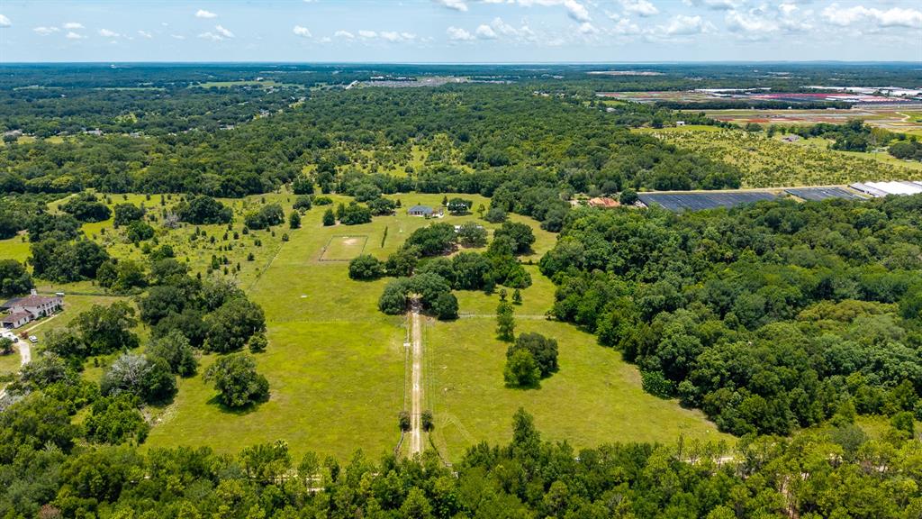 An aerial view shows a large, grassy rural property with a long driveway and trees — 21341 HORSE RANCH ROAD, MOUNT DORA, FL