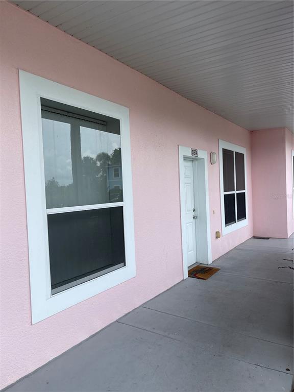 A pink exterior wall features two windows and a white door along a concrete walkway — 3157 SUN LAKE COURT UNIT A, KISSIMMEE, FL