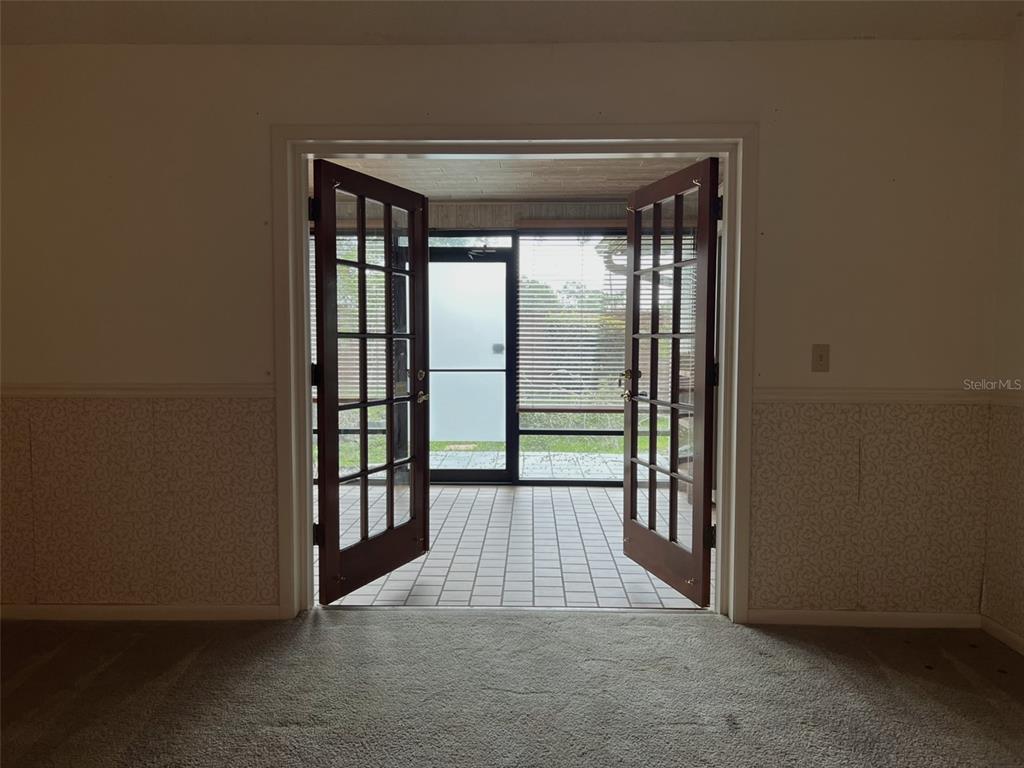 A carpeted room opens through French doors to a tiled, screened-in porch — 6328 N QUEENSWAY DRIVE, TEMPLE TERRACE, FL