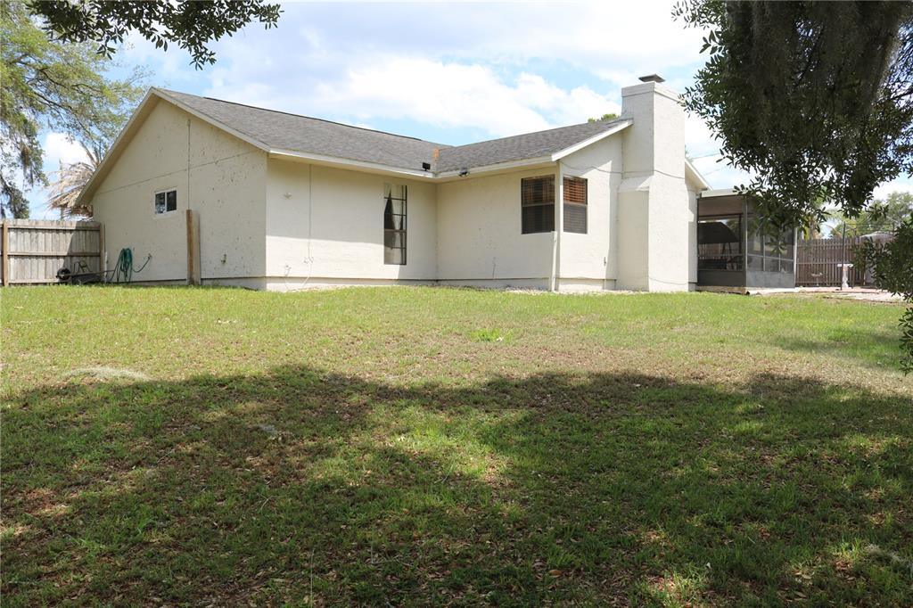 A beige, single-story house with a chimney and a screened-in porch in the backyard — 2392 BRIMHALL COURT, DELTONA, FL