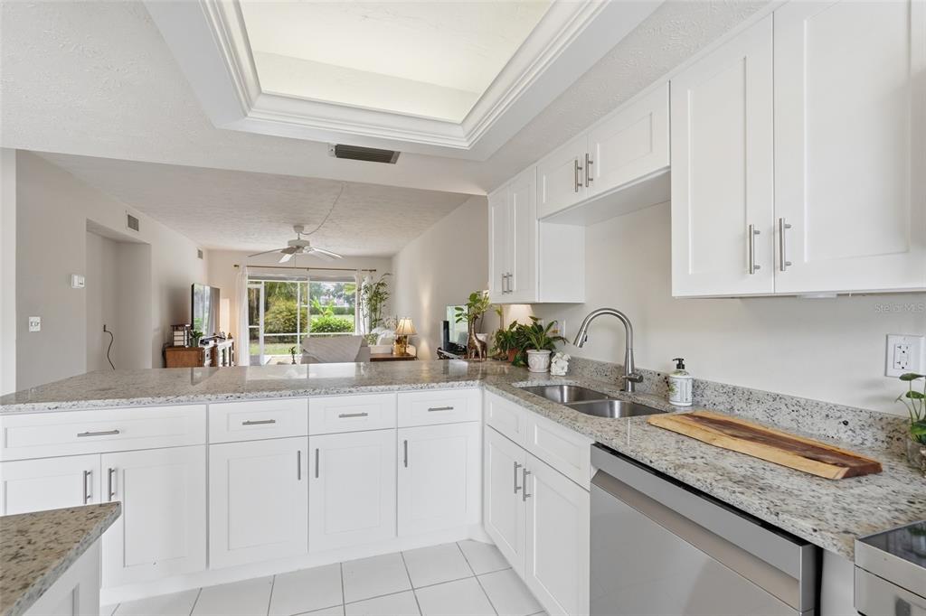 A kitchen with white cabinets, granite countertops, and a view into the living room — 16211 DUBLIN CIRCLE UNIT 104, FORT MYERS, FL