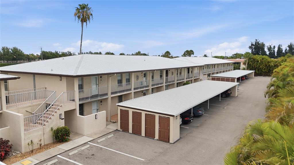 An exterior view of a two-story apartment building with covered parking and a metal roof — 16211 DUBLIN CIRCLE UNIT 104, FORT MYERS, FL