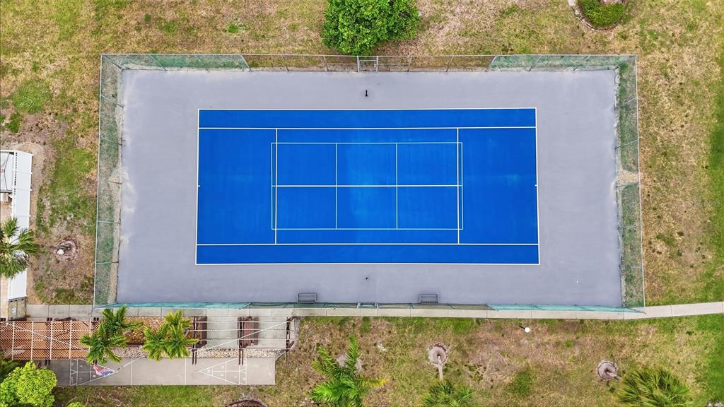 An aerial view shows a blue tennis court enclosed by a chain-link fence — 16211 DUBLIN CIRCLE UNIT 104, FORT MYERS, FL