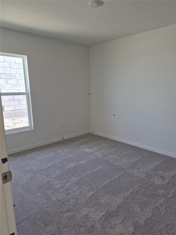 An empty bedroom features white walls, gray carpeting, a single window, and a recessed light — 3016 CASCADE CIRCLE, LAKE WALES, FL