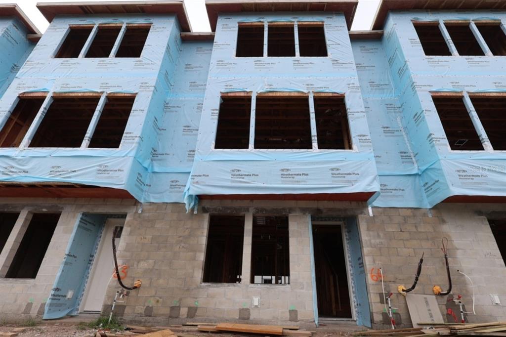 The exterior of a multi-story townhome under construction features concrete block walls and blue housewrap — 3104 4TH PLACE N, ST PETERSBURG, FL