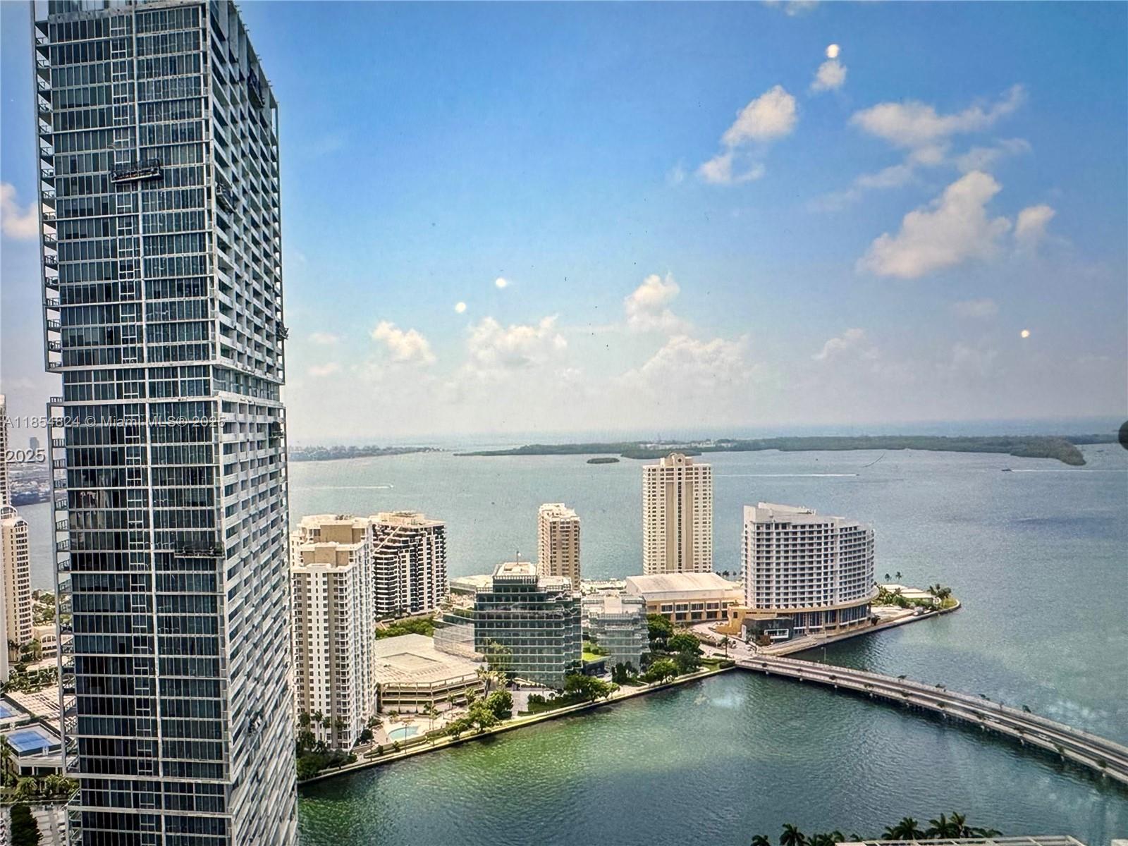 An elevated view of a coastal city skyline featuring a tall skyscraper and a bridge — 500 Brickell Ave # 1204, Miami FL 33131, MIAMI, FL