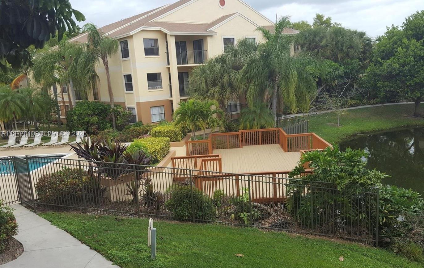 An elevated wooden deck overlooks a pond and a multi-story apartment building — 9999 Summerbreeze Dr # 420, Sunrise FL 33322, SUNRISE, FL