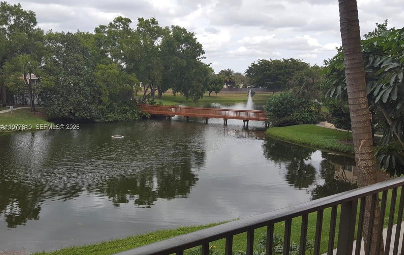 A wooden footbridge spans a pond with a fountain, viewed from a balcony — 9999 Summerbreeze Dr # 420, Sunrise FL 33322, SUNRISE, FL