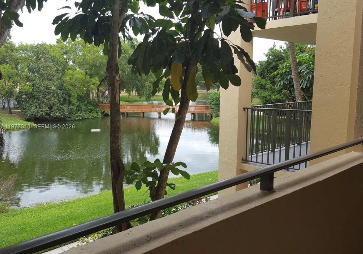 A view from a balcony overlooking a lake and a wooden footbridge — 9999 Summerbreeze Dr # 420, Sunrise FL 33322, SUNRISE, FL