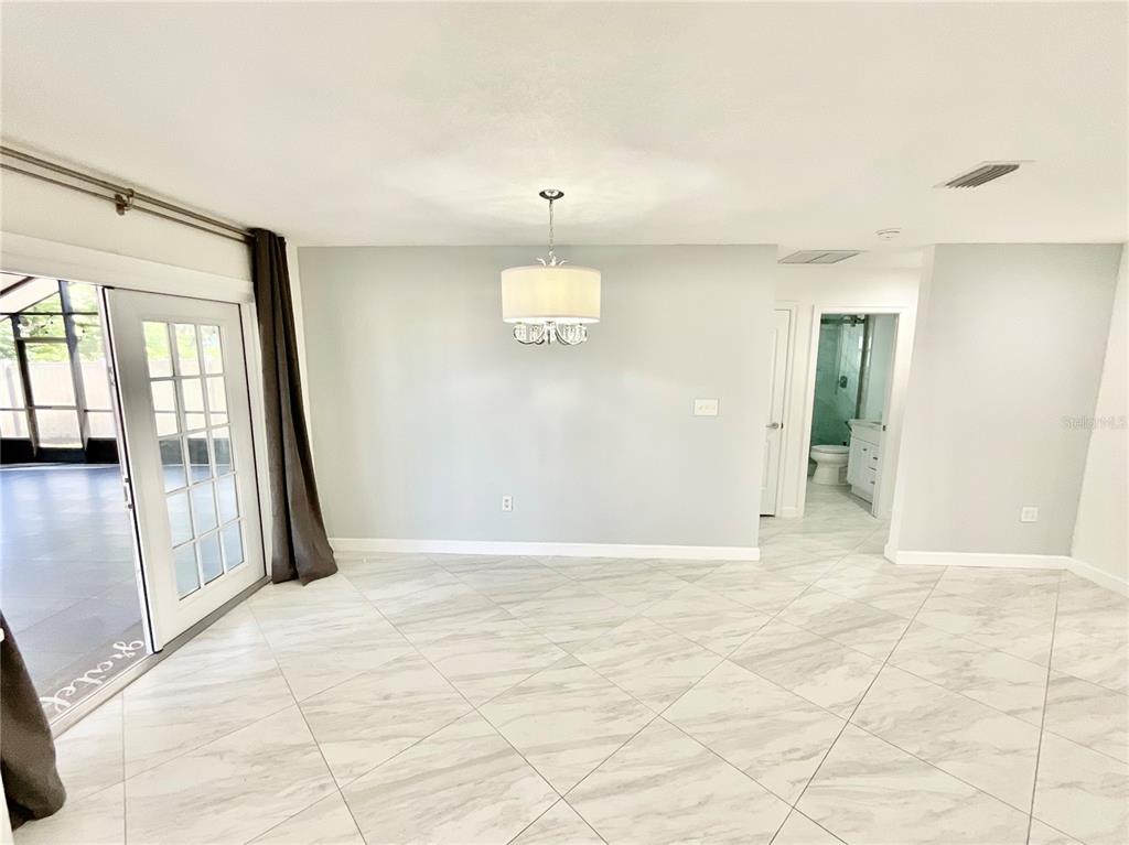 A dining area features light gray walls, white tile flooring, and a modern drum chandelier — 1545 INDIANA AVENUE, PALM HARBOR, FL