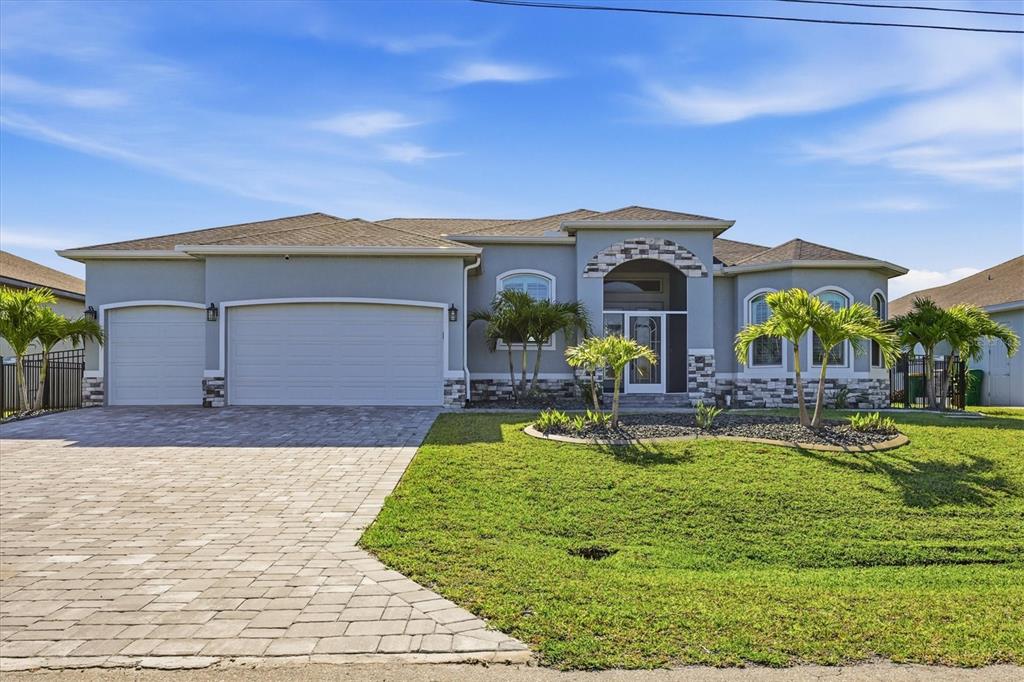 A single-story house with a gray stucco exterior, stone accents, and a paved driveway — 8314 TRACY CIRCLE, PORT CHARLOTTE, FL
