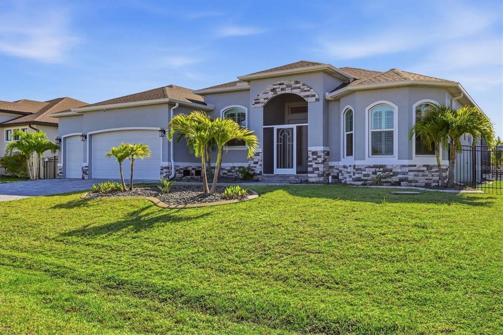 A single-story suburban house with a gray stucco exterior, stone accents, and a two-car garage — 8314 TRACY CIRCLE, PORT CHARLOTTE, FL
