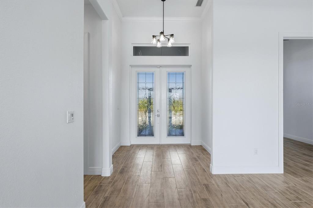 A bright entryway features white walls, wood-look tile flooring, and double glass-paneled front doors — 8314 TRACY CIRCLE, PORT CHARLOTTE, FL