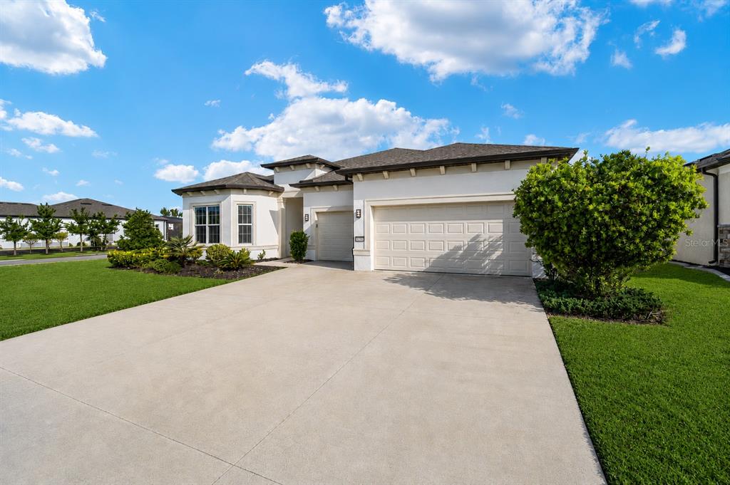 A single-story house with a beige stucco exterior, a three-car garage, and a concrete driveway — 8828 SW 61ST LOOP, OCALA, FL