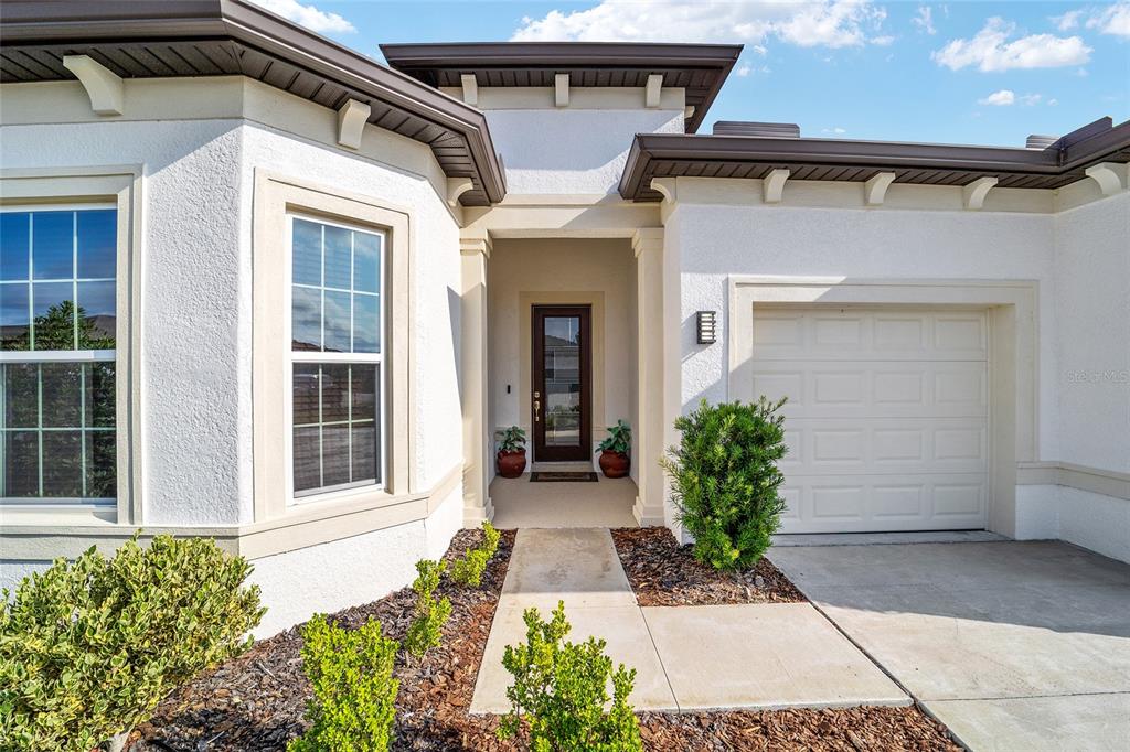 The exterior of a white stucco house features a front entrance, garage, and landscaping — 8828 SW 61ST LOOP, OCALA, FL
