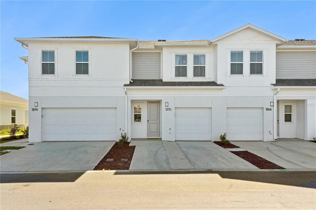 A row of three white two-story townhomes with attached garages and concrete driveways — 1898 ZAC STREET UNIT Sunset, KISSIMMEE, FL
