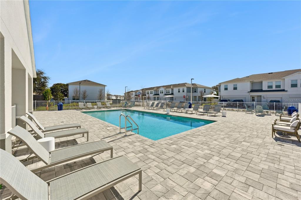 A swimming pool with lounge chairs on a paved deck surrounded by residential buildings — 1898 ZAC STREET UNIT Sunset, KISSIMMEE, FL