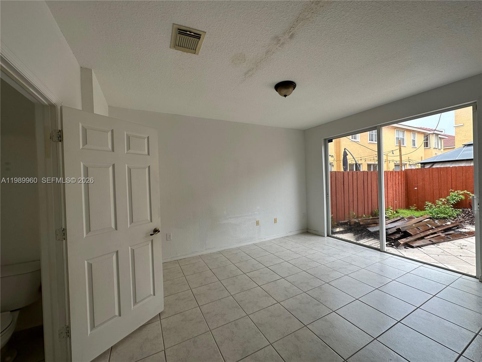 A room with white walls, tile flooring, a sliding glass door, and a ceiling vent — 16602 SW 78th Ter, Miami FL 33193, MIAMI, FL