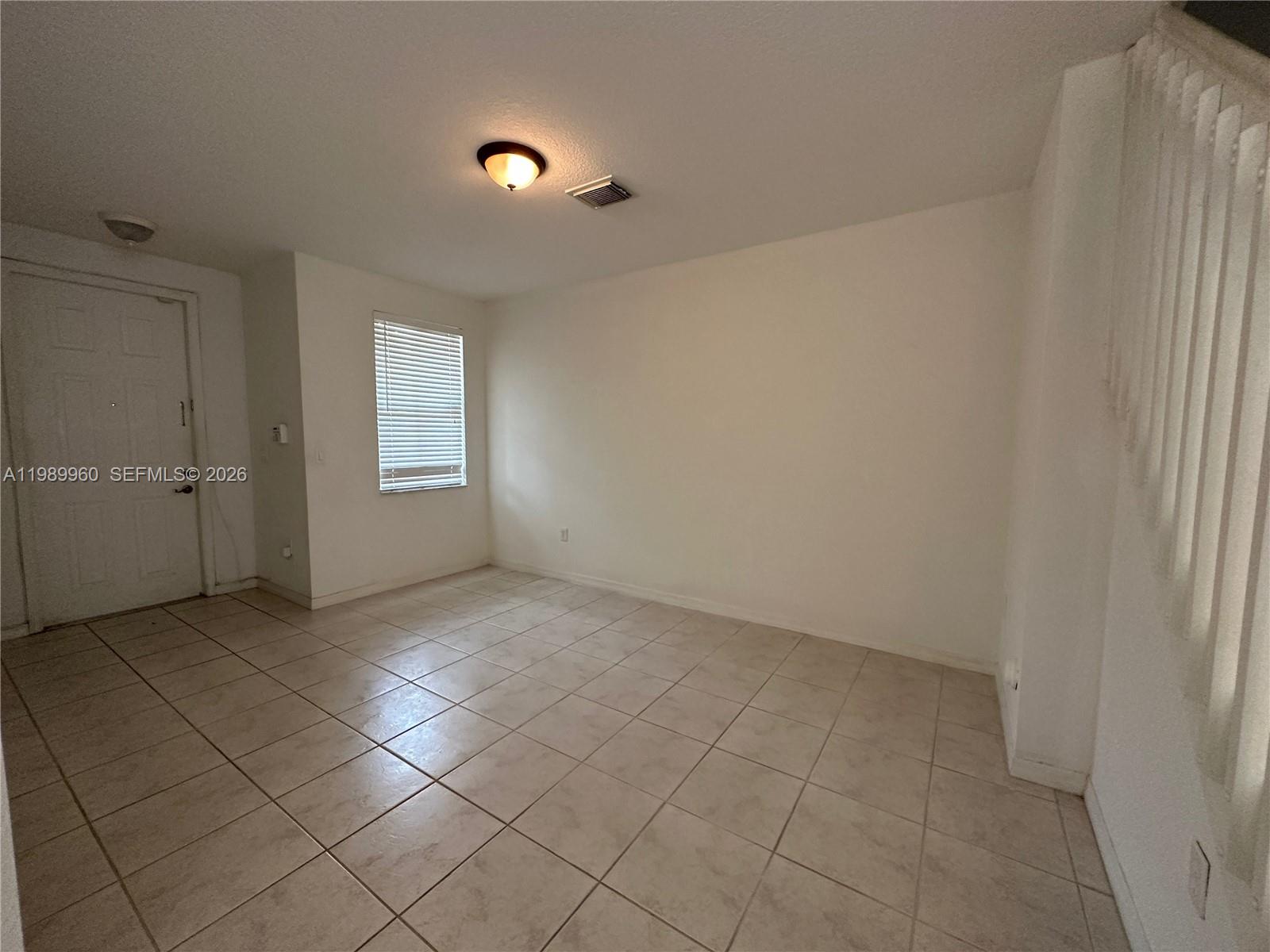 An empty room features white walls, beige tile flooring, a single window, and a ceiling light — 16602 SW 78th Ter, Miami FL 33193, MIAMI, FL